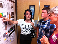 Two students point and talk to their poster.